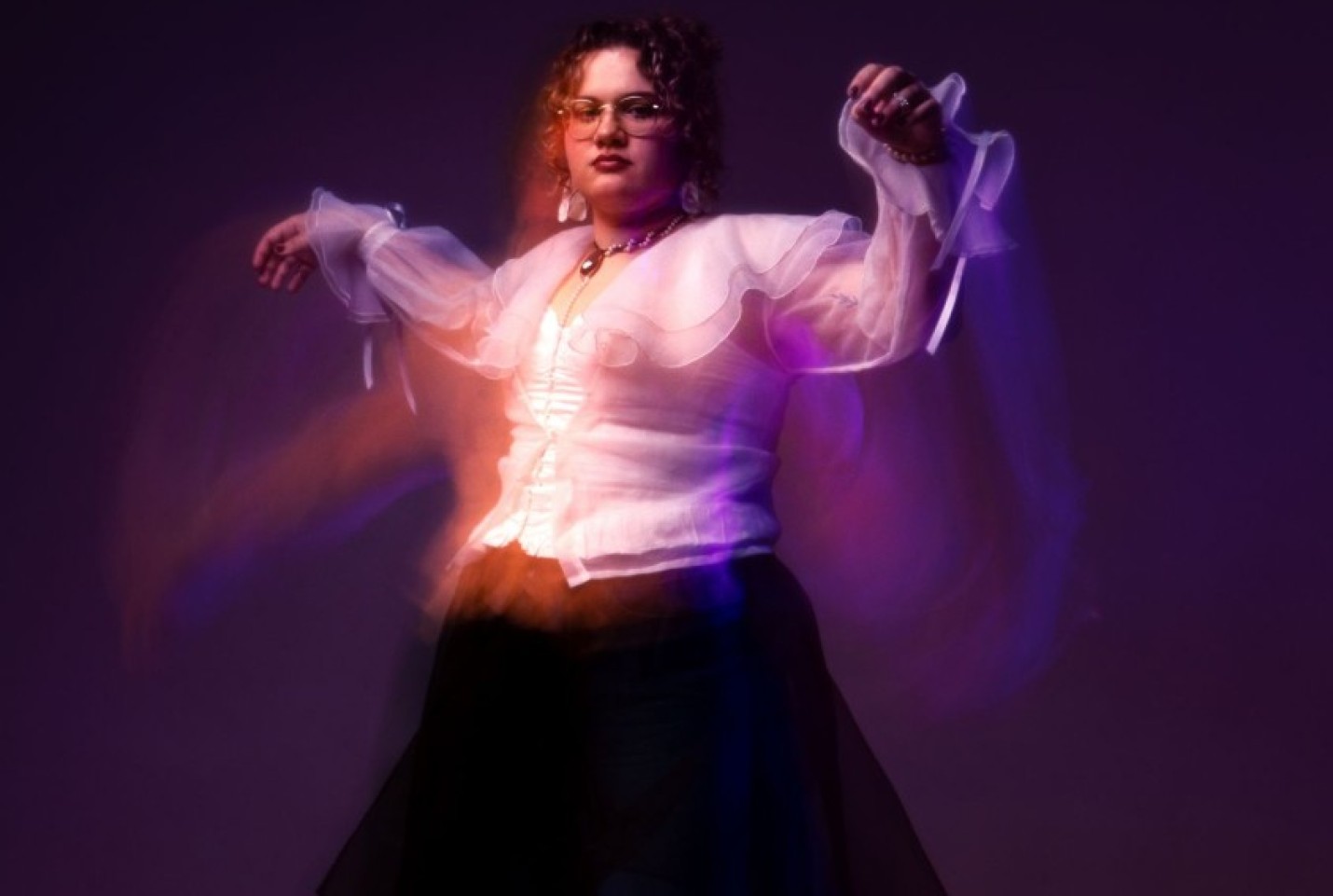 Billianne in a white top and black skirt dancing.